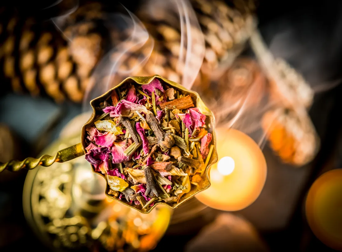 Goldene Schale mit Räuchermischung zwischen Kerzen und Tannenzapfen